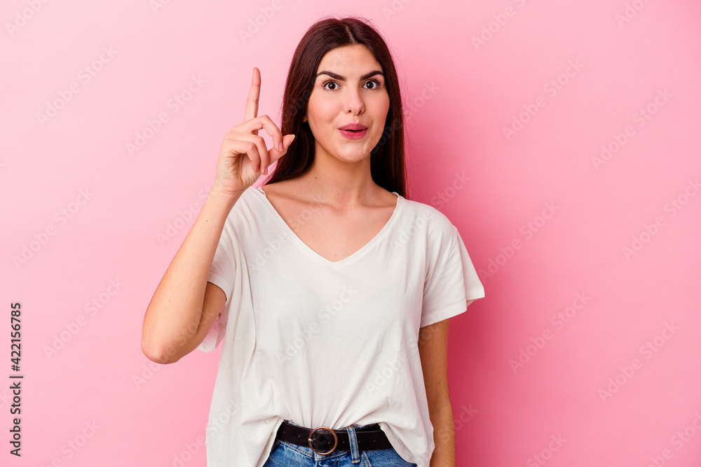 Young caucasian woman isolated on pink background pointing upside with opened mouth. Young caucasian woman isolated on pink background pointing upside with opened mouth.