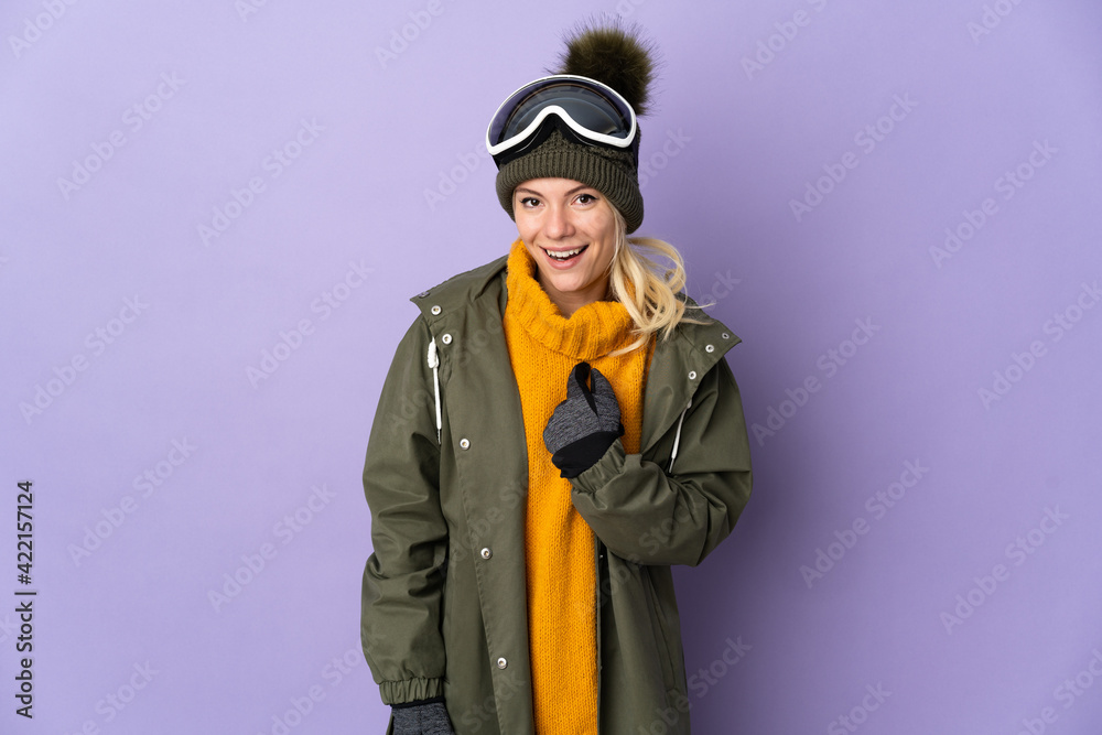 Skier Russian girl with snowboarding glasses isolated on purple background with surprise facial expression
