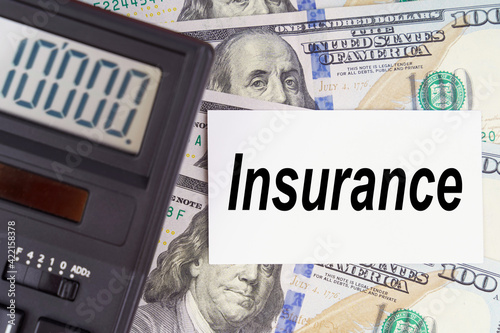 On the table are dollars, a calculator and a business card with the inscription Insurance