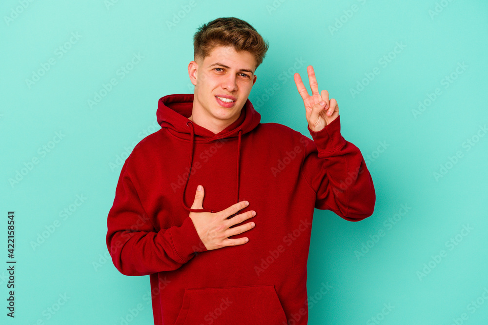 Young caucasian man isolated on blue background taking an oath, putting hand on chest. Young caucasian man isolated on blue background taking an oath, putting hand on chest.