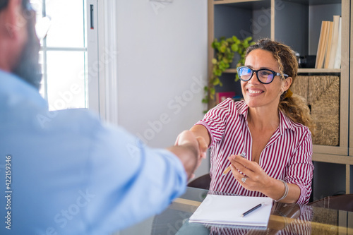 Smiling caucasian female hr manager handshake hire male candidate at job interview make good first impression, happy mixed race client shake hand of bank broker, respect, business agreement concept
 photo