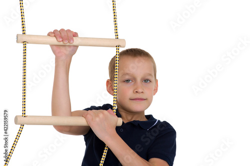 Teenage boy climbiing on rope ladder. Photo session in the studio photo