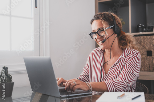 Attractive caucasian woman sit at homeoffice room wearing headset take part in educational webinar using laptop. Video call event with clients or personal chat with friend remotely concept. photo