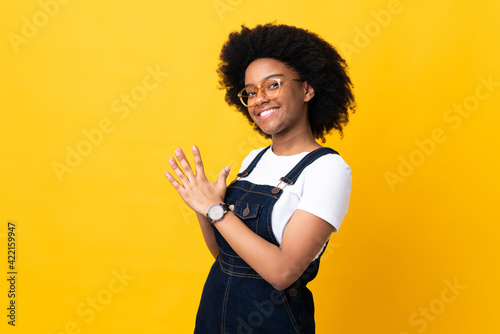 Young African American woman isolated on yellow background scheming something
