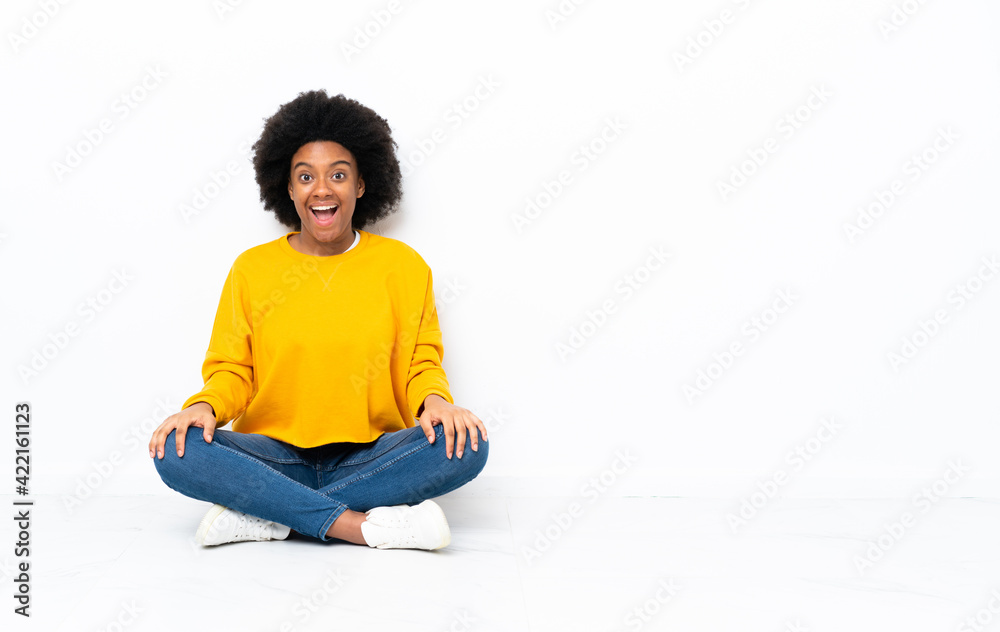 Young African American woman sitting on the floor with surprise facial expression Young African American woman sitting on the floor with surprise facial expression