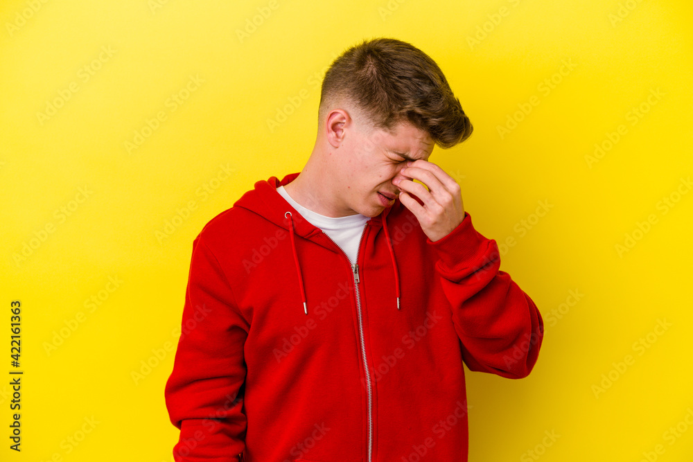 Young caucasian man isolated on yellow background having a head ache, touching front of the face. Young caucasian man isolated on yellow background having a head ache, touching front of the face.