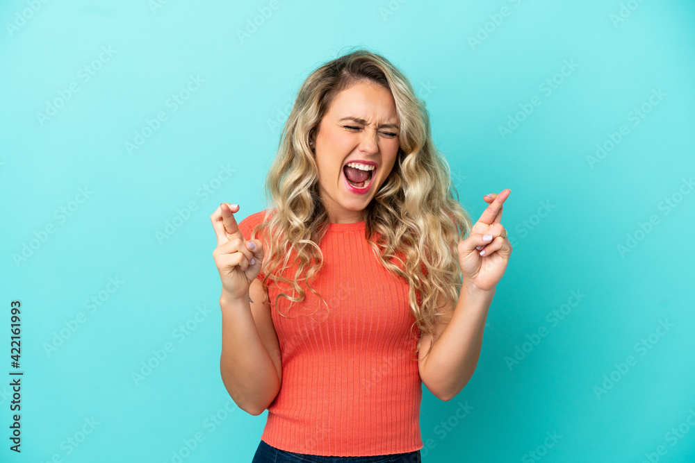 Young Brazilian woman isolated on blue background with fingers crossing Young Brazilian woman isolated on blue background with fingers crossing