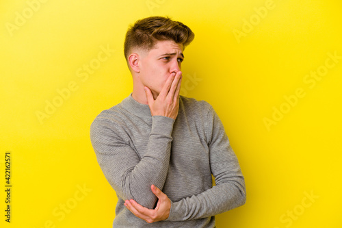 Young caucasian man isolated on yellow background yawning showing a tired gesture covering mouth with hand. © Asier
