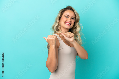 Young Brazilian woman isolated on blue background pointing to the side to present a product