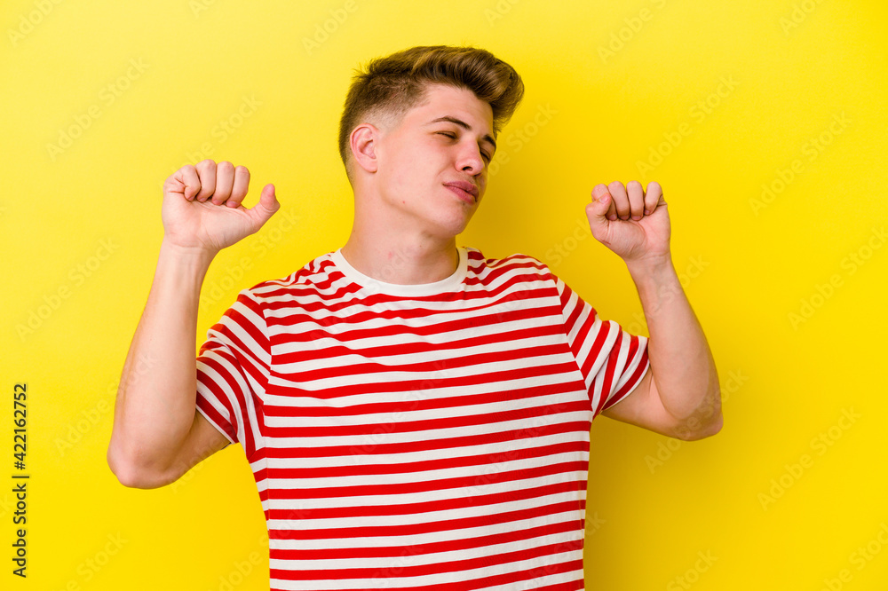Young caucasian man isolated on yellow background celebrating a special day, jumps and raise arms with energy. Young caucasian man isolated on yellow background celebrating a special day, jumps and raise arms with energy.