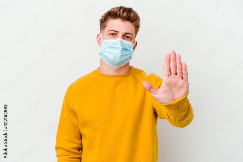 Young man wearing a mask for coronavirus isolated on white background standing with outstretched hand showing stop sign, preventing you. Young man wearing a mask for coronavirus isolated on white background standing with outstretched hand showing stop sign, preventing you.