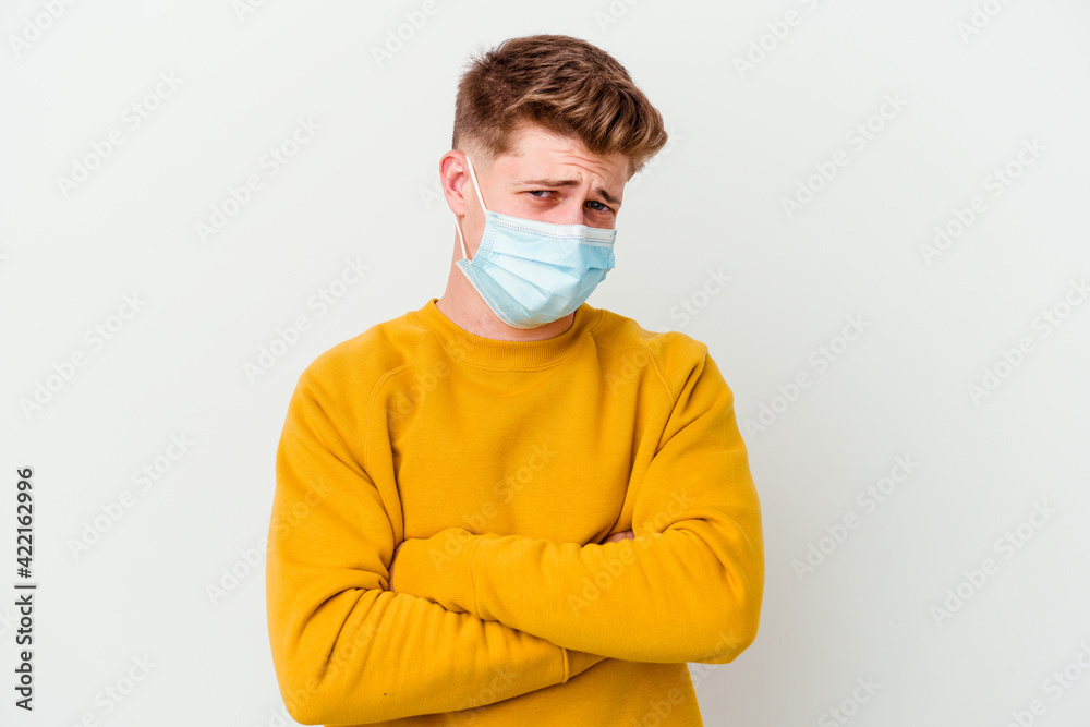 Young man wearing a mask for coronavirus isolated on white background frowning face in displeasure, keeps arms folded. Young man wearing a mask for coronavirus isolated on white background frowning face in displeasure, keeps arms folded.