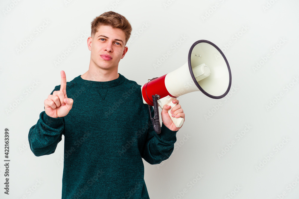 Young caucasian man holding a megaphone isolated on white background showing number one with finger. Young caucasian man holding a megaphone isolated on white background showing number one with finger.
