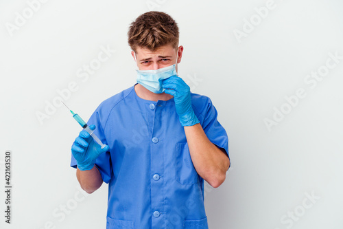 Young caucasian nurse man prepared to give a vaccine isolated on white background biting fingernails  nervous and very anxious.