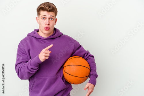 Young caucasian man playing basketball isolated background pointing to the side