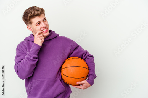 Young caucasian man playing basketball isolated background relaxed thinking about something looking at a copy space.