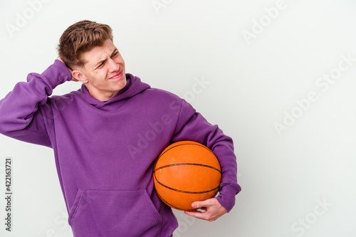 Young caucasian man playing basketball isolated background touching back of head, thinking and making a choice.