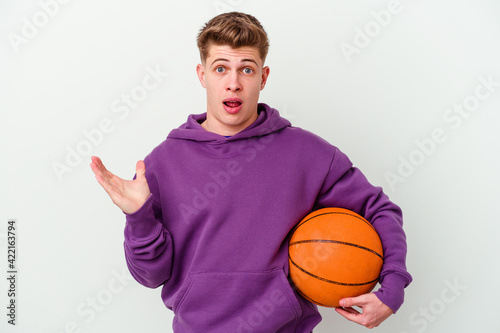 Young caucasian man playing basketball isolated background surprised and shocked.