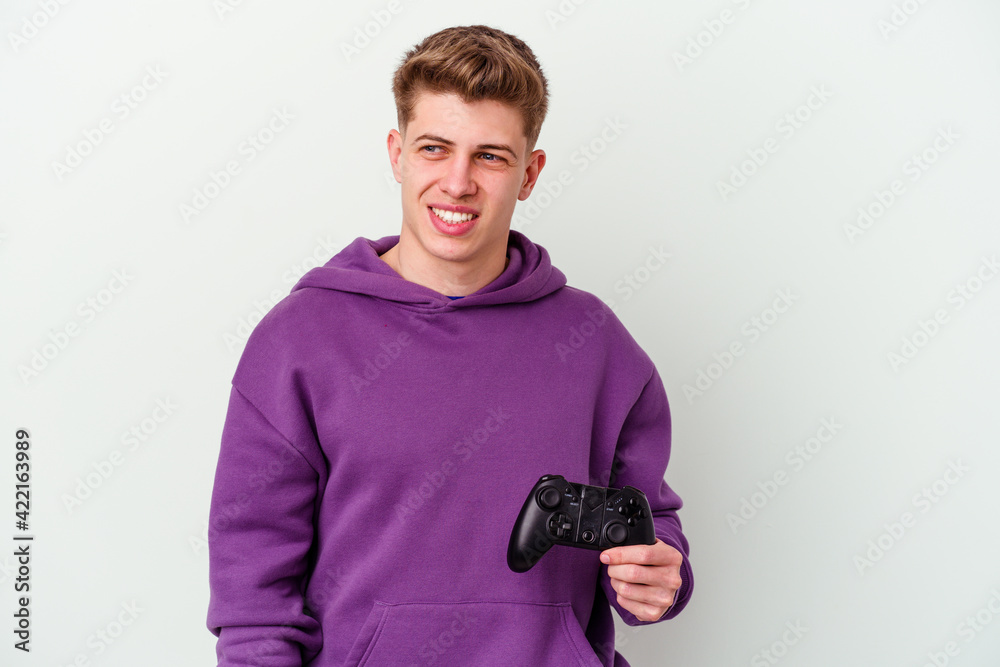 Young caucasian man holding a gamepad isolated on white background looks aside smiling, cheerful and pleasant. Young caucasian man holding a gamepad isolated on white background looks aside smiling, cheerful and pleasant.