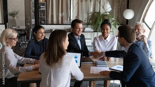 Принти на полотні Smiling male colleagues coworkers shake hands close deal at meeting with multiracial employees in office