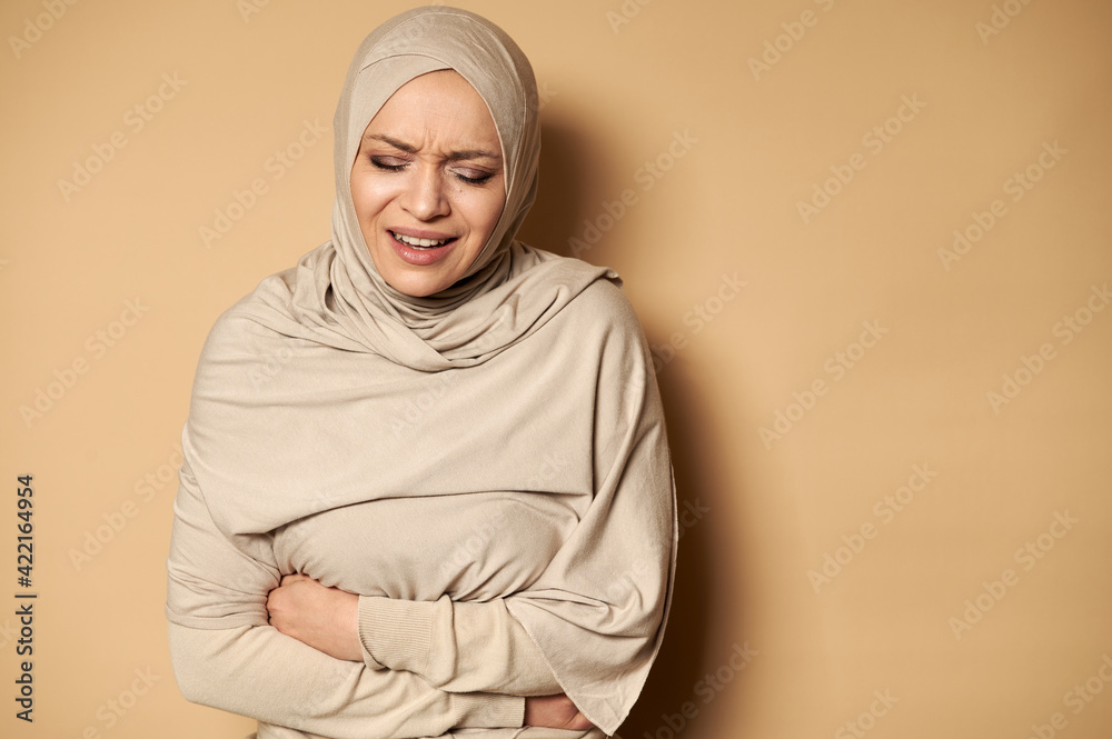 Young Muslim woman in hijab suffering from abdominal pain Young Muslim woman in hijab suffering from abdominal pain