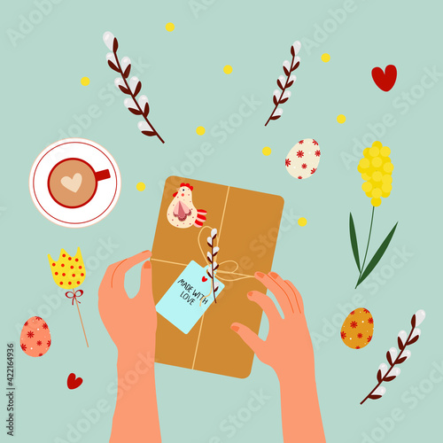 Female hands wrapping the Easter gift. Trendy illustration of hands, gift box, painted eggs and willow branch on the table, top-down view. Hand-drawn modern illustration for web and print.