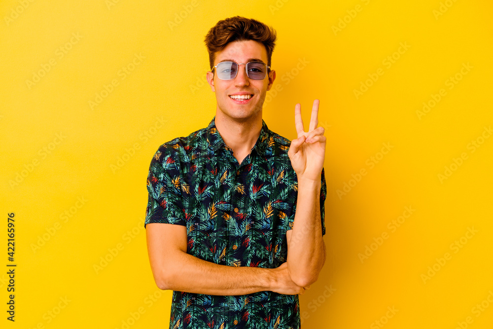 Young caucasian man wearing a Hawaiian shirt isolated on yellow background showing number two with fingers. Young caucasian man wearing a Hawaiian shirt isolated on yellow background showing number two with fingers.