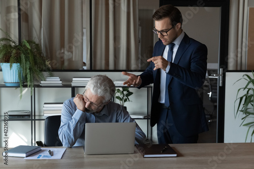 Obraz na plátně Angry young Caucasian male boss or CEO lecture scold middle-aged employee at workplace