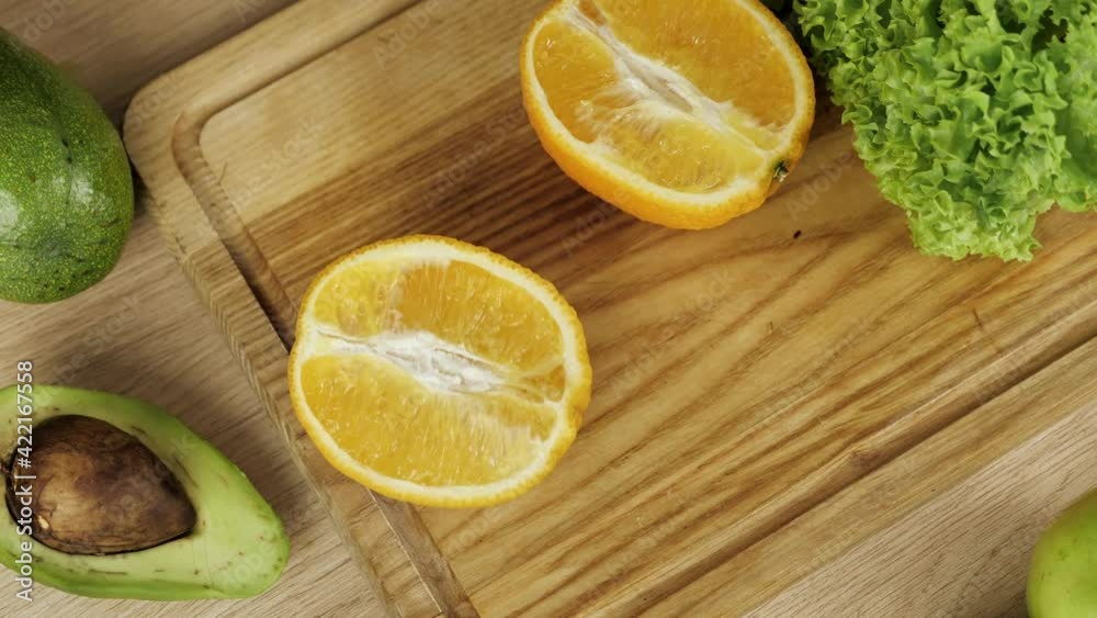 Woman's peels orange. Sliced orange and avocados on the table. Diet, few calories, vegetarianism, natural vitamins. Woman's peels orange. Sliced orange and avocados on the table. Diet, few calories, vegetarianism, natural vitamins.