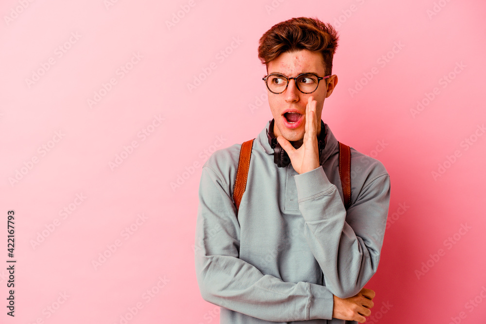 Young student man isolated on pink background is saying a secret hot braking news and looking aside Young student man isolated on pink background is saying a secret hot braking news and looking aside