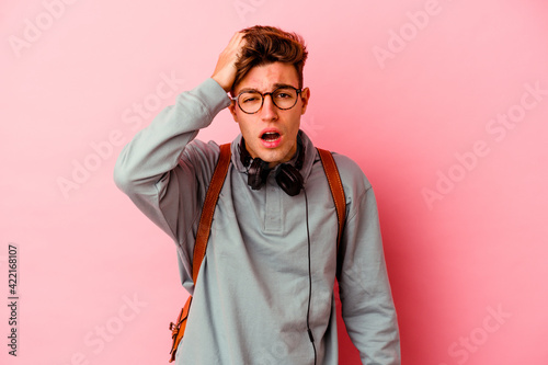 Young student man isolated on pink background tired and very sleepy keeping hand on head. © Asier