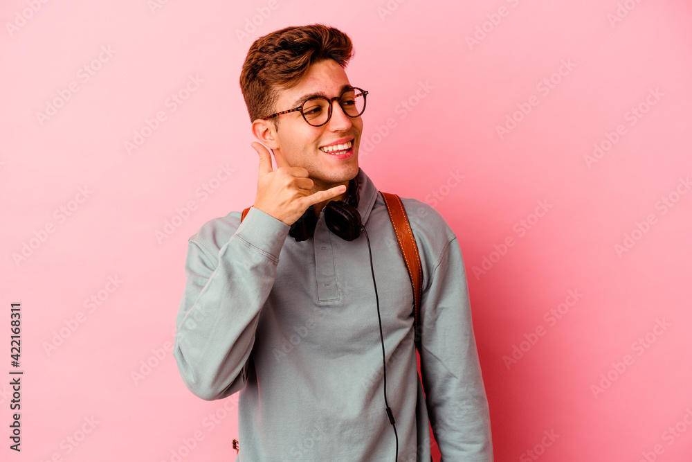Young student man isolated on pink background showing a mobile phone call gesture with fingers.