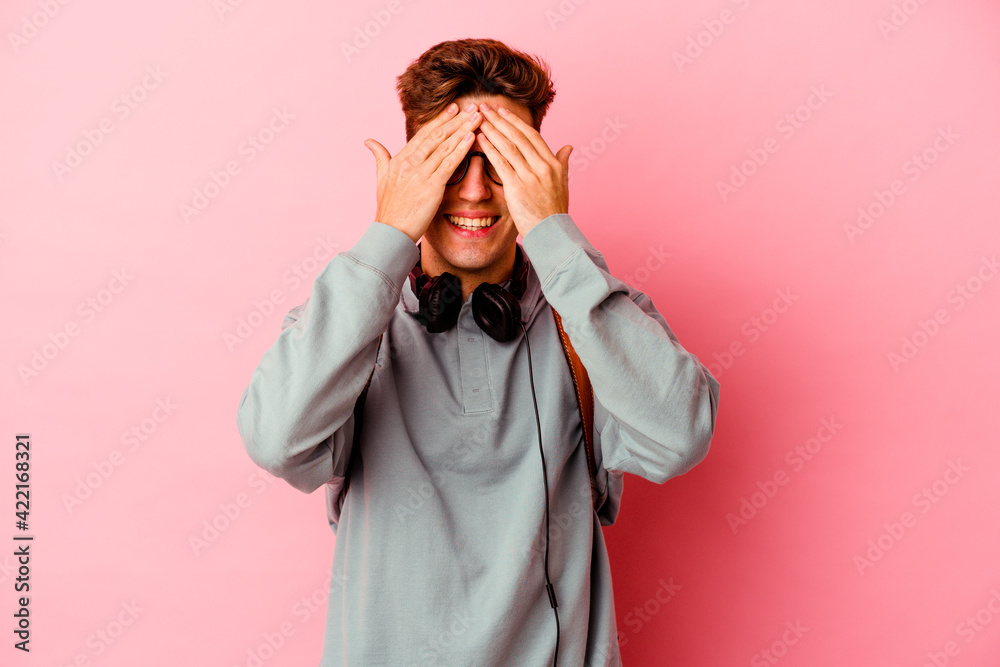 Young student man isolated on pink background covers eyes with hands, smiles broadly waiting for a surprise. Young student man isolated on pink background covers eyes with hands, smiles broadly waiting for a surprise.