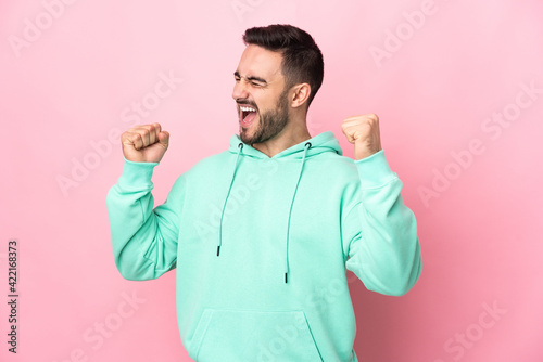 Young caucasian handsome man isolated on pink background celebrating a victory © luismolinero