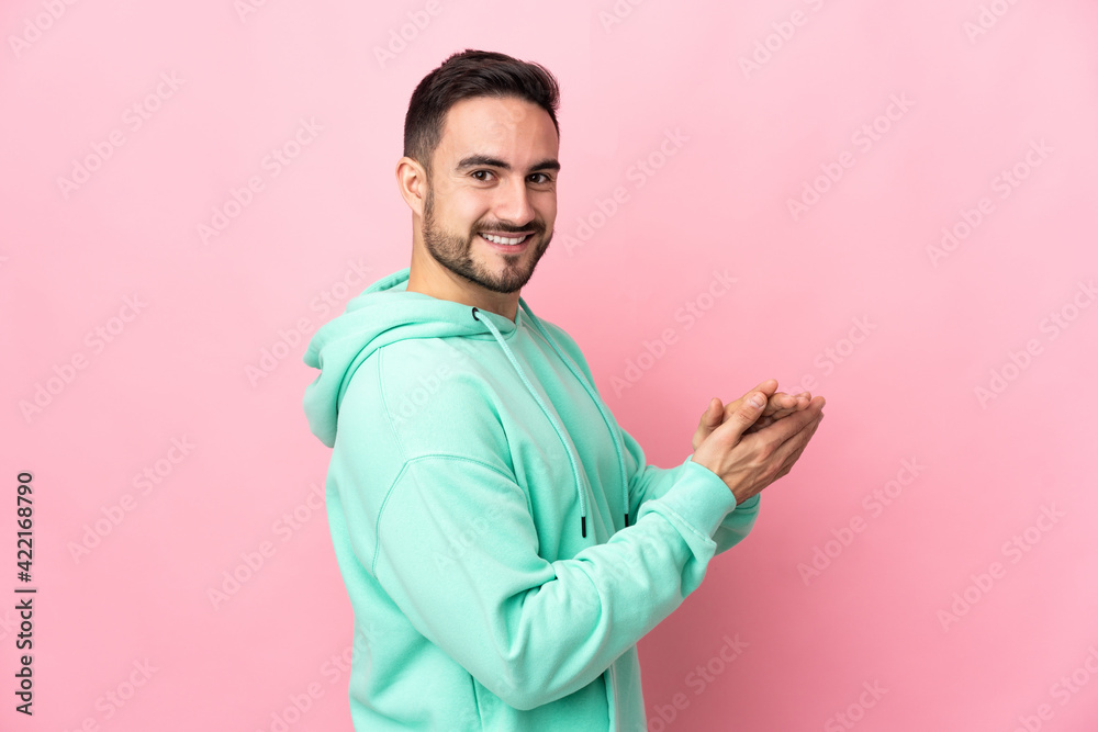 Young caucasian handsome man isolated on pink background applauding