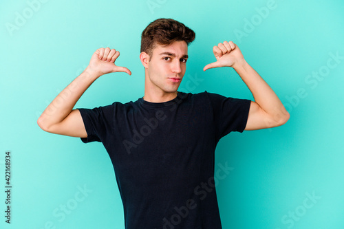 Young caucasian man isolated on blue background feels proud and self confident, example to follow.