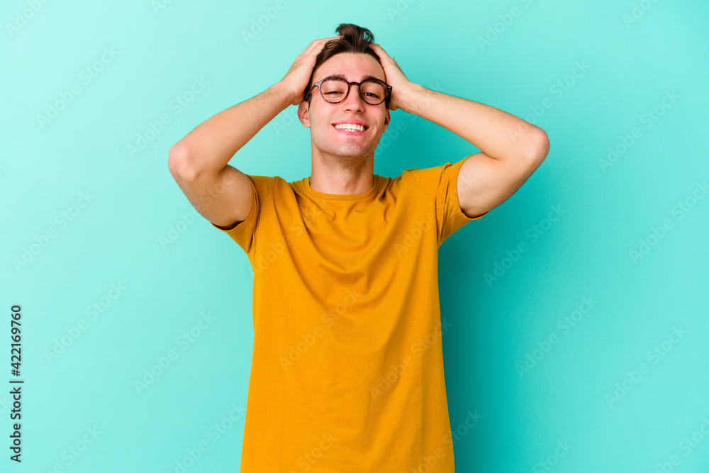 Young caucasian man isolated on blue background laughs joyfully keeping hands on head. Happiness concept. Young caucasian man isolated on blue background laughs joyfully keeping hands on head. Happiness concept.