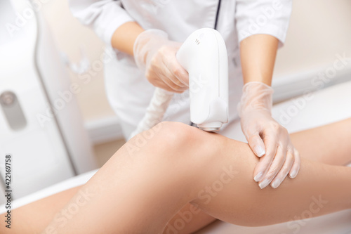 Master removes hair with laser from legs of beautiful woman, health and beauty care spa