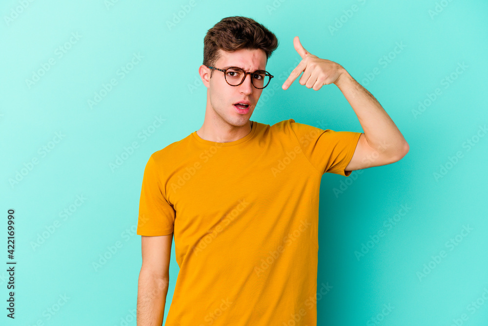 Young caucasian man isolated on blue background person pointing by hand to a shirt copy space, proud and confident Young caucasian man isolated on blue background person pointing by hand to a shirt copy space, proud and confident