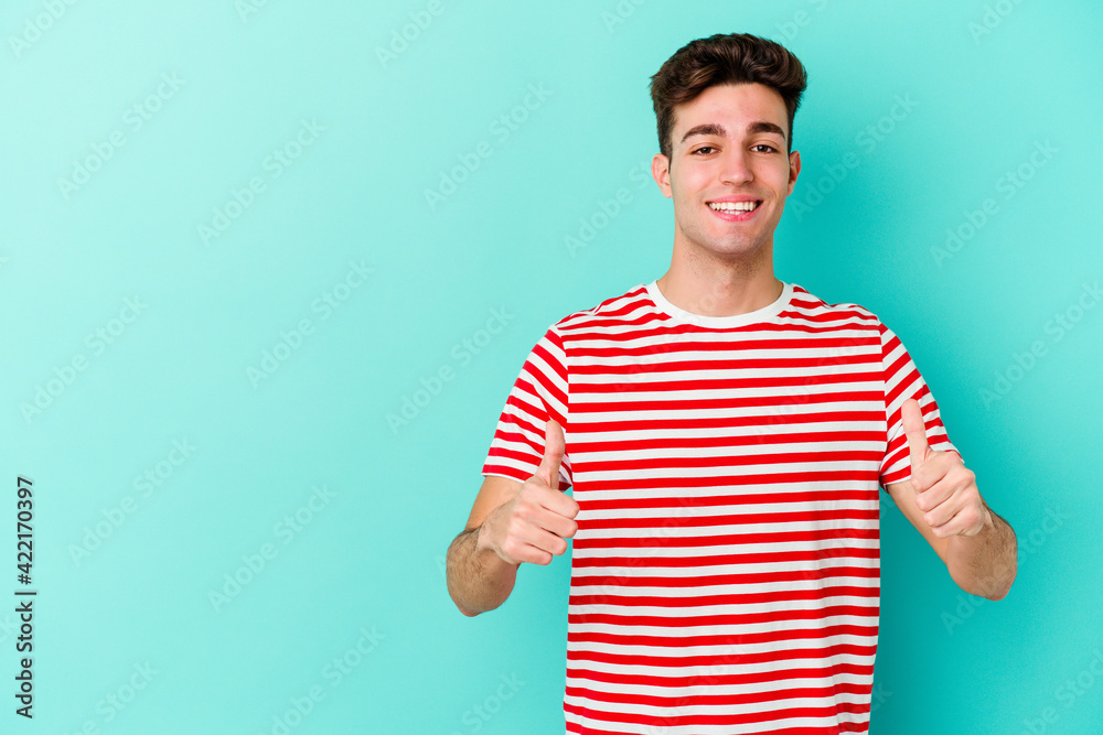 Young caucasian man isolated on blue background smiling and raising thumb up Young caucasian man isolated on blue background smiling and raising thumb up