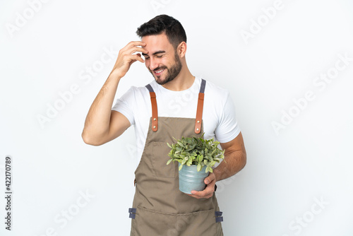 Gardener man holding a plant isolated on white background laughing