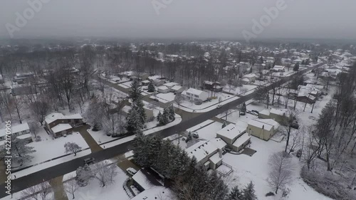 A drone flys over Strongsville, Ohio which is a suburb of Cleveland.  It's winter time in the midwestern town.  Snow covers the once lush grass.  photo