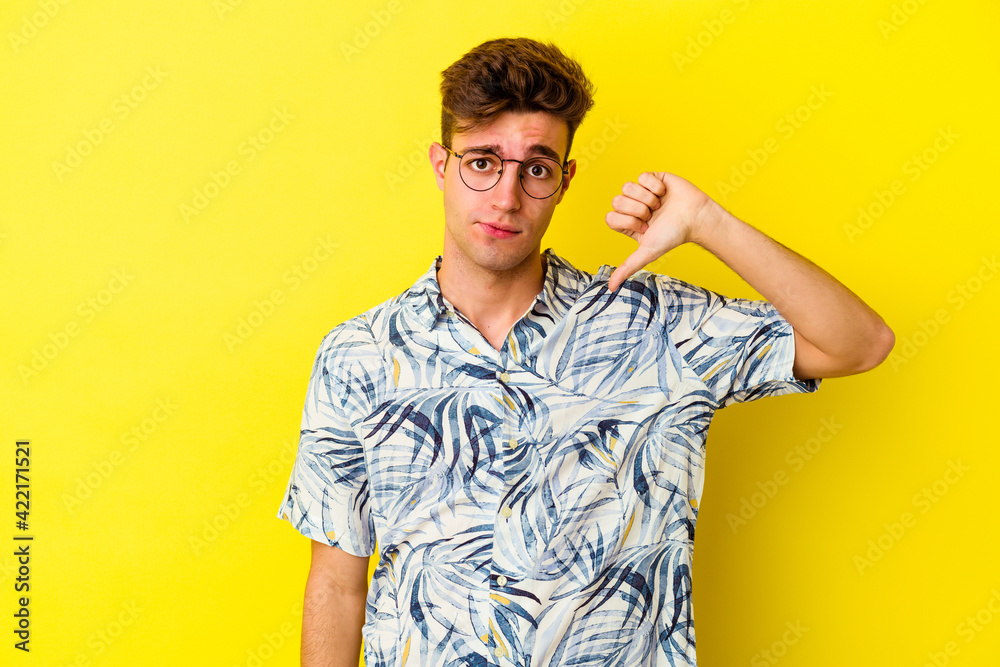 Young caucasian man isolated on yellow background showing thumb down, disappointment concept. Young caucasian man isolated on yellow background showing thumb down, disappointment concept.