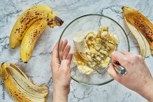 Woman hand mashing up several bananas photo