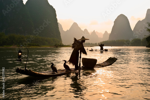 Cormorant fishermen on the Li River (Lijiang) with karst peaks in the background at sunset, near Xingping, Guangxi Province, China
