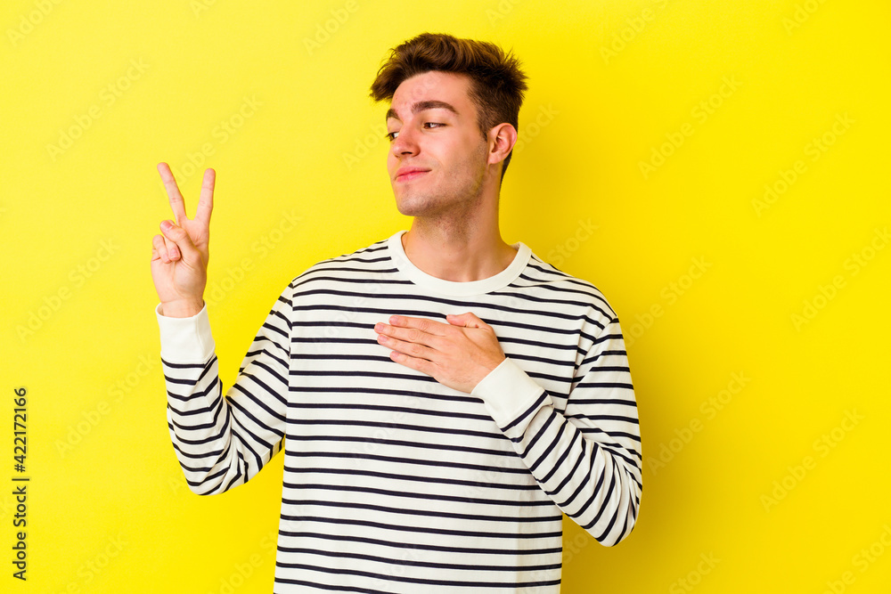 Young caucasian man isolated on yellow background taking an oath, putting hand on chest. Young caucasian man isolated on yellow background taking an oath, putting hand on chest.