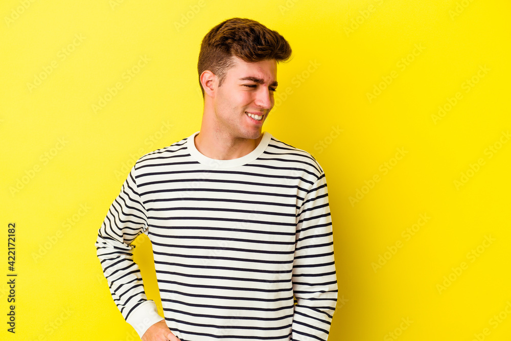 Young caucasian man isolated on yellow background laughs and closes eyes, feels relaxed and happy. Young caucasian man isolated on yellow background laughs and closes eyes, feels relaxed and happy.