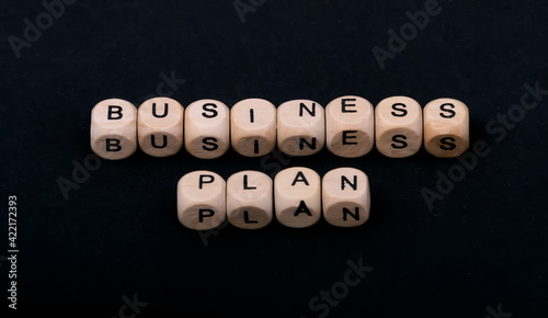 Wooden cubes on a black background with the words business plan