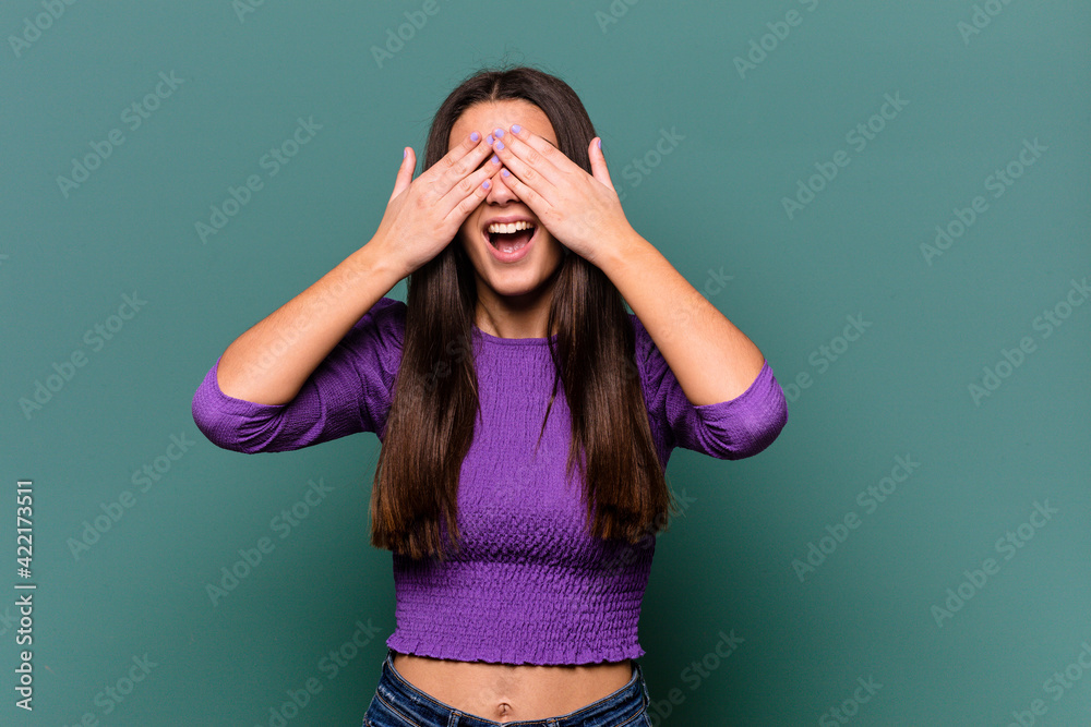Young Indian woman isolated on blue background covers eyes with hands, smiles broadly waiting for a surprise. Young Indian woman isolated on blue background covers eyes with hands, smiles broadly waiting for a surprise.