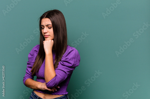 Young Indian woman isolated on blue background looking sideways with doubtful and skeptical expression.